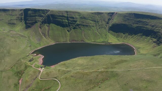 Aerial view of a lake at the foot of large cliffs (Llyn y Fan Fach)