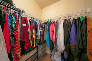Small walk in closet with hanging colorful clothes on a metal rods