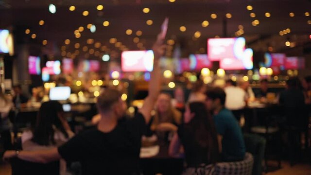 Group of people sitting and chatting at table after end of lockdown in bar or pub