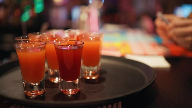 Close view over bunch of red or orange shots at bar counter in pub