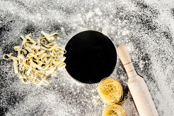 Freshly cooked pasta is lying on a dark surface dusted with flour. Italian pasta. Tagliatelle. Raw pasta. Italian pasta recipe. Top view, copy space