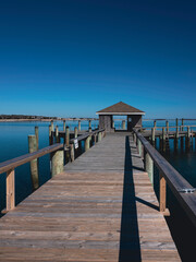 Obraz premium Wooden boardwalk and dock house stretching out into the sea. Seascape of Hyannis Harbor in Massachusetts.