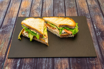 Spanish village loaf bread sandwich with chicken breast fillet with ripe avocado, tomatoes and mayonnaise with vegetables