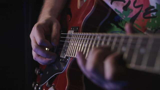Playing guitar arp chord notes. Musician plays the guitar during a live performance. right hand playing guitar in a bluish lightning. guitar player at a concert rocking audience. just a guitarist