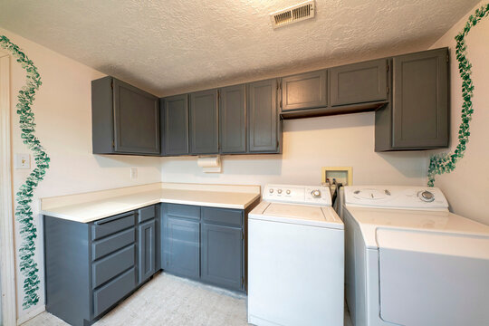 Laundry room exterior with laundry units and gray colored cabinets and drawers