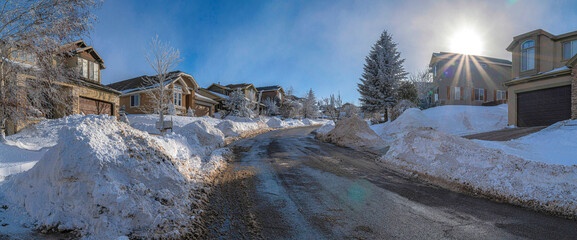Uphill curved road cleared of snow in a residential area at Utah