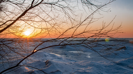 Fototapeta premium View of the sunset on a frozen lake covered by the thick ice in Ontario, Canada.