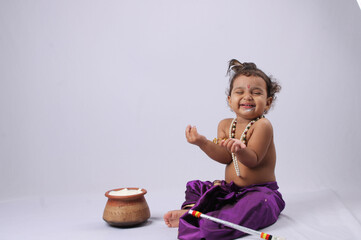adorable Indian baby in krishna kanha or kanhaiya dress posing with his flute and dahi handi (pot...