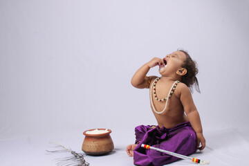 adorable Indian baby in krishna kanha or kanhaiya dress posing with his flute and dahi handi (pot...