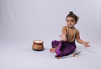 adorable Indian baby in krishna kanha or kanhaiya dress posing with his flute and dahi handi (pot...