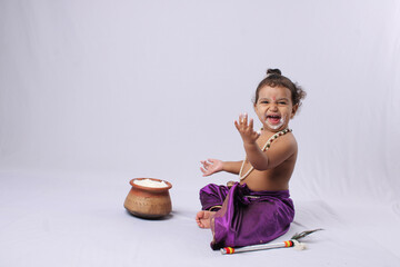 adorable Indian baby in krishna kanha or kanhaiya dress posing with his flute and dahi handi (pot...