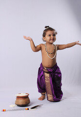 adorable Indian baby in krishna kanha or kanhaiya dress posing with his flute and peacock feather...