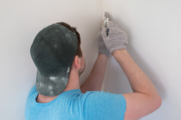 Senior man with putty knife plastering repairing wall