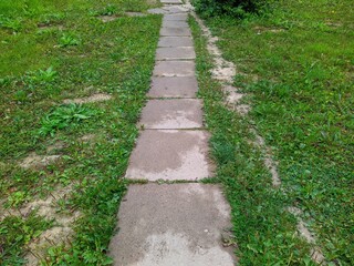 path in the park is made of concrete square slabs.