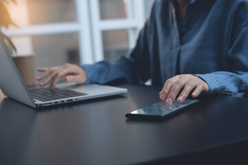 Fototapeta premium Casual businesswoman, multitasking woman, working on laptop computer and using mobile phone at home