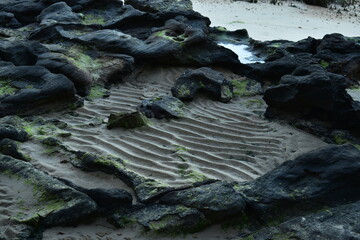 ripples in sand amongst rocks on the beach