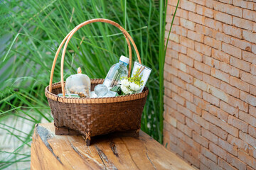 The Stuffs in a wicker basket for offer food or give alms to the monks on a wooden chair with the brick wall background.