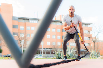 Low angle view of a sportsman exercising with a trx fitness strap in the park