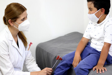 Female pediatrician doctor examining a 7-year-old Latino boy in her office
