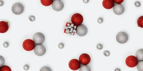 Christmas banner with bright baubles decorations, red and silver colored balls and gift box with tinsel bow on white background