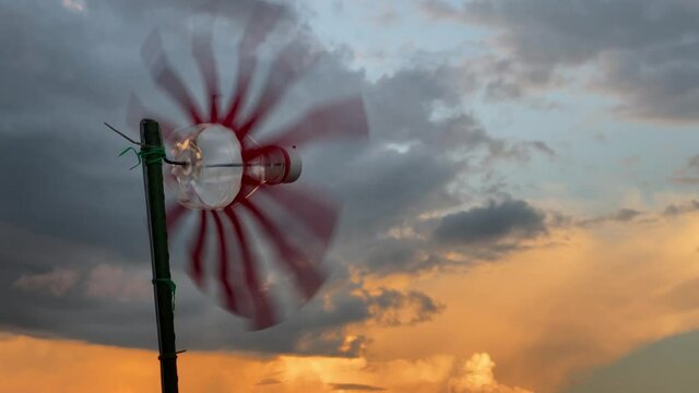 夕暮れ空の下で回転するアルミ缶風車