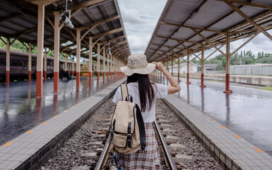 Fototapeta na wymiar Traveler woman tourist hand holding hat and backpack and holding tourist map walking on the railway at the train station. Active and travel lifestyle concept.