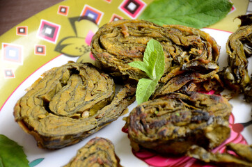 closeup the fried arabic leaves food with green mint in the plate over out of focus white pink background.
