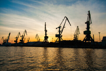 Obraz premium Silhouettes of cranes in the seaport at sunset.