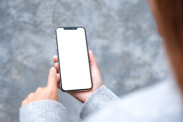 Mockup image of a woman holding mobile phone with blank white desktop screen in the outdoors