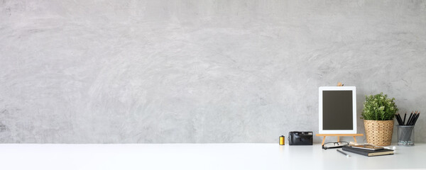 Mock up tablet, camera, books and houseplant on white table.