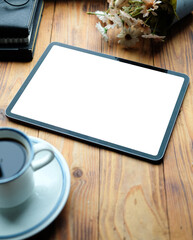 Mock up digital tablet with white screen and coffee cup on wooden table.