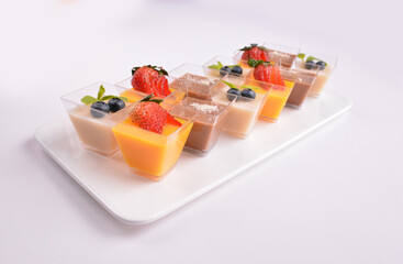 mini chilled pudding jelly with mango, coffee chocolate, almond lychee flavour with fresh fruits on top in cup in white background for Christmas festival menu