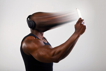 African man athlete on a light background uses a smartphone. The man's face is transferred, sucked,...