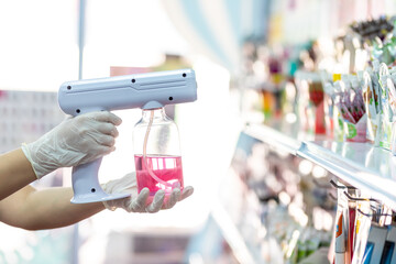 close up hand of staff wearing gloves using portable usb nano sanitizer spray disinfectant machine...