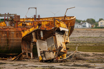 A rusty shipwreck in the mud of the Walney Channel, seen from the road to Roa Island, Cumbria, England, UK