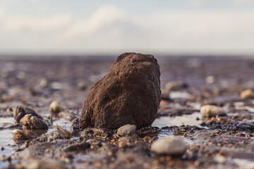 A large stone surrounded by smaller stones in Snettisham Beach, Norfolk, England, UK
