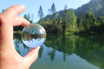 Reflektion in einer Glaskugel von einem See und Bäumen in den Bergen 