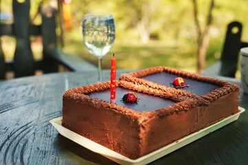 Birthday cake and glass of wine on the table in nature