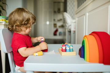 Little boy playing with wooden toy figures at the table