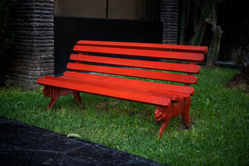 Banca o banqueta roja en el jardín de la casa