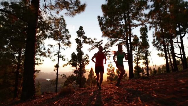 Running fitness and health . Runners on run training during fitness workout outside in mountain forest at sunset. People jogging together living healthy active lifestyle outside. Woman and man