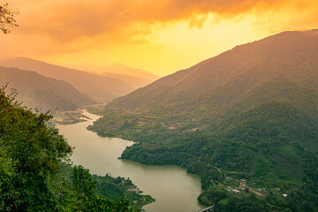 mountain river leading to the valley at dawn with dramatic orange sky