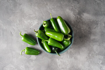 Green jalapeno peppers in a plate on a gray background. Top view. - obrazy, fototapety, plakaty