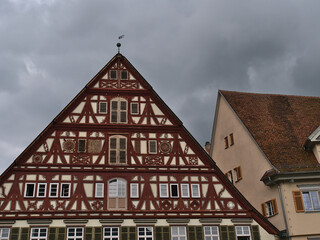Gable of old half-timbered house at the town square of Esslingen am Neckar, Baden-Württemberg, Germany on cloudy summer day. Text on facade: Year of construction (1582) and names of builders.