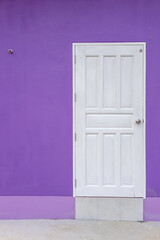 White wooden door with purple concrete wall.