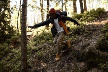 Active tourist explore unknown path in forest, falling from hill. Sunlight fall on trees, virgin...