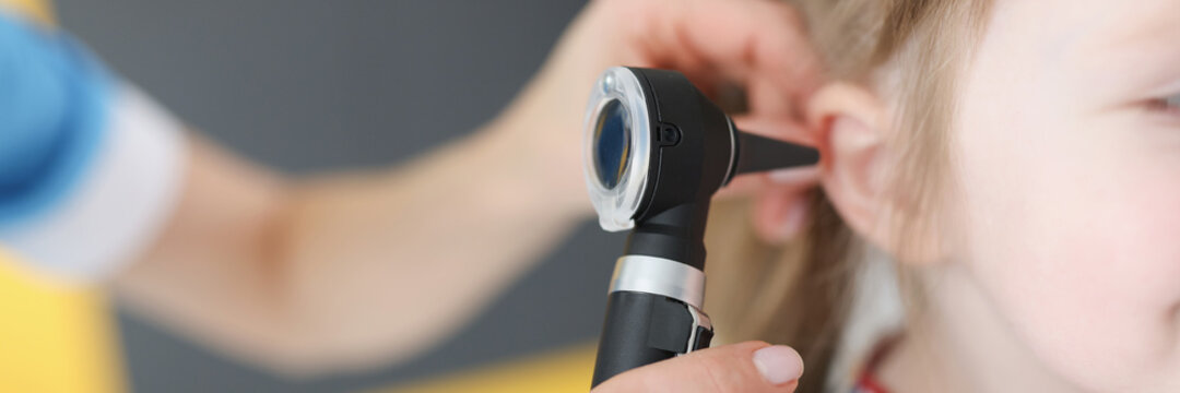 Doctor examines ear drum of little girl