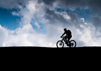 Fototapeta na wymiar Mountain Biker as silhouette in front of clouds
