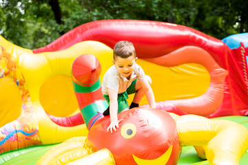 Little boy child having fun and jumping on an inflatable trampoline in the park.