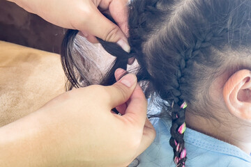 Mother braided hair her daughter at home